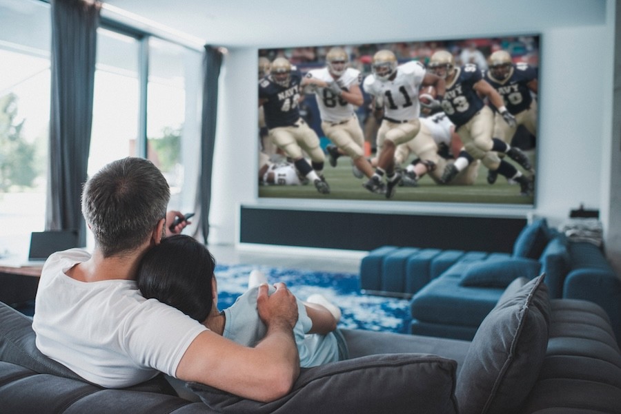 A couple watching football on a high definition TV in their media room.