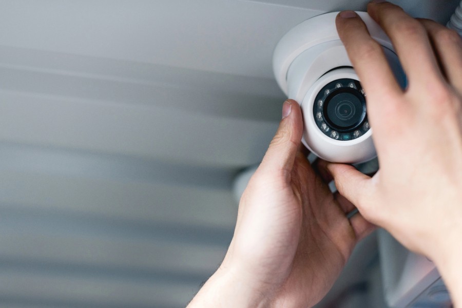 A person mounting a security camera on a wall.