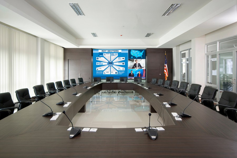 A boardroom with an LED video wall, a large table, and chairs.