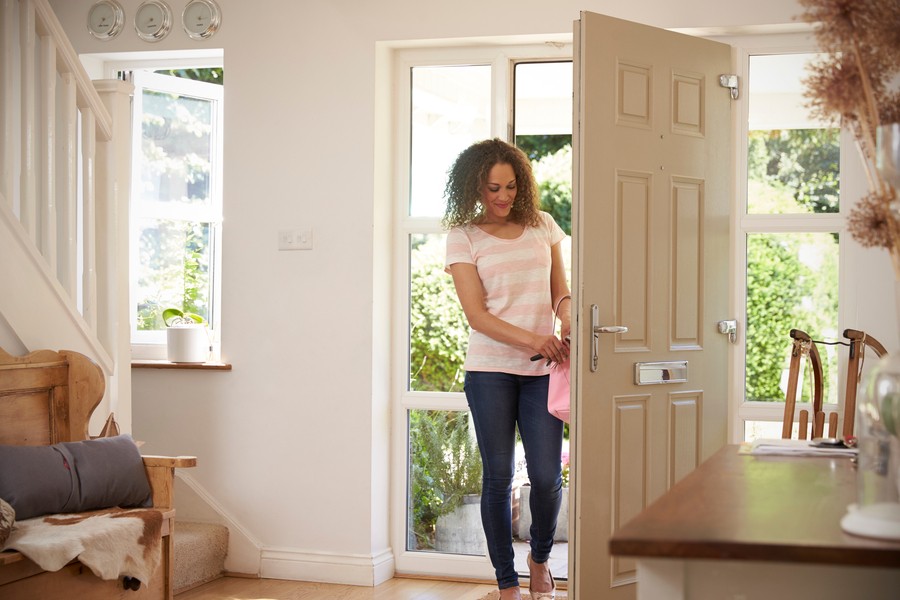 A woman entering her home through the front door.