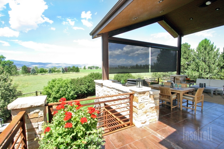 An outdoor shade rolled halfway down on a patio. 