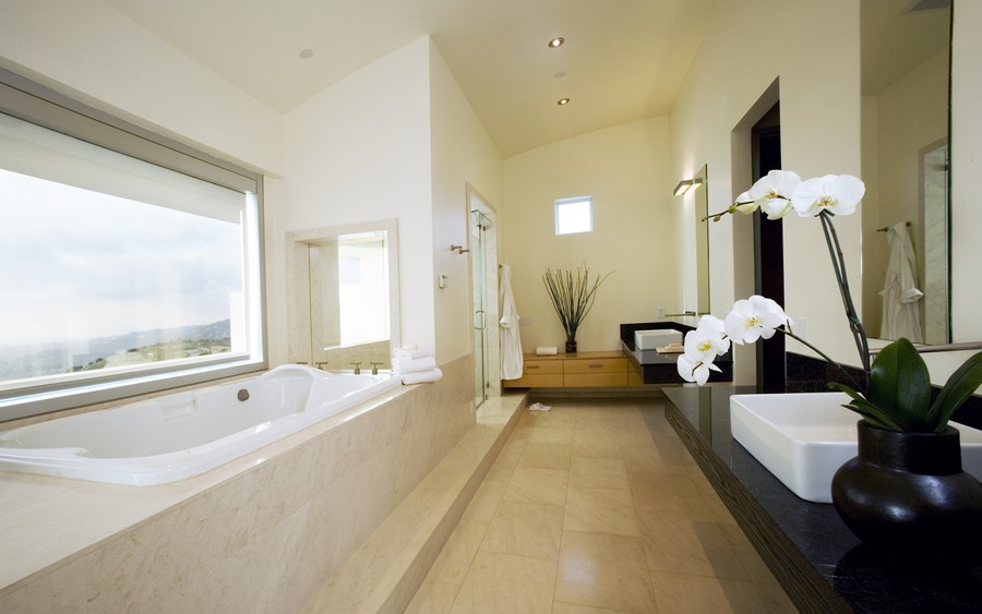 Bathroom with tub overlooking a window with motorized shades on one side and a sink on the other