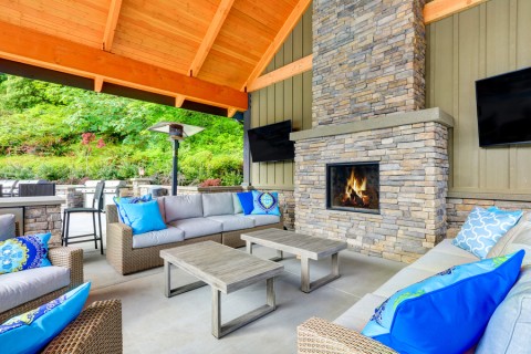 outdoor seating area with on-wall TV entertainment, coffee table, and a space heater