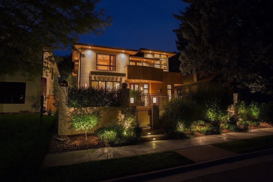 A roadside view of a gated smart home at night. 