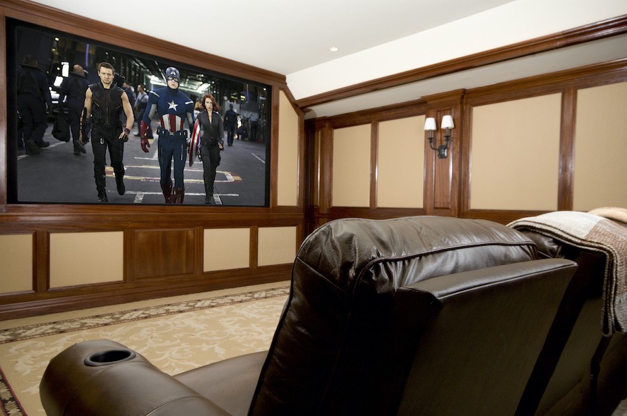A custom home theater displays an Avengers movie on the big screen.
