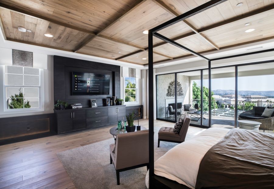 A bedroom with in-ceiling speakers and a Control4 display on the TV screen.