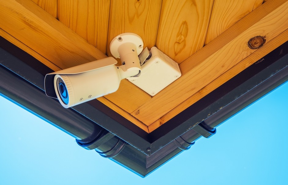 Bullet camera mounted on a wooden ceiling outdoors. 