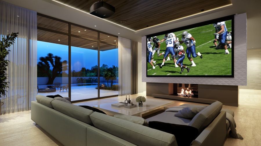 A living room with a Sony projector, in-ceiling speakers, and a large screen displaying a football game.